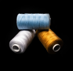 Fototapeta na wymiar Sewing thread - yarn - rolls in different colors - blue, white, gold