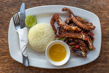 Fried octopus tentacles with white rice on a plate, close up