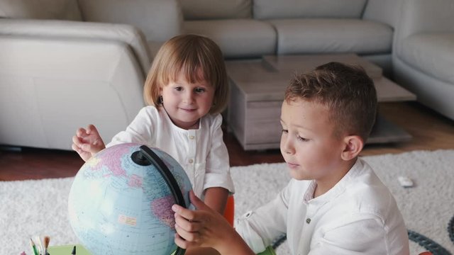 The children are playing with the globe. They are learning the oceans. The kids are holding the globe.