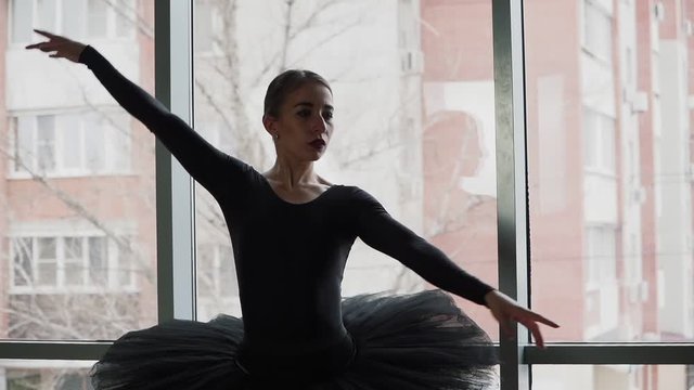ballerina on a background of the city a beautifully moving dance. In a black tutu and Pointe shoes. The image of the black Swan from the ballet. Slow motion