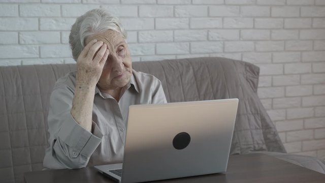 Woman with computer difficulty. Granny is at a loss in front of a laptop.