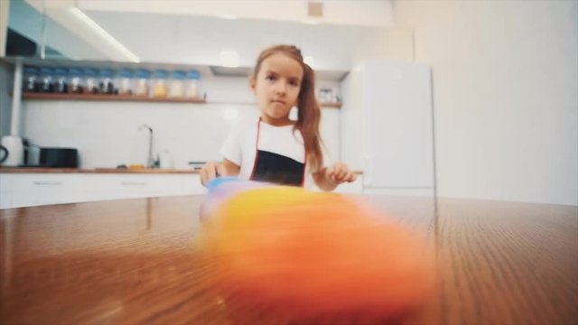Little, cute girl wipes the kitchen table with a dust cleaner. Close up. 4K.