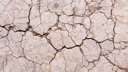 Broken land or close-up arid  ground. Photo of land in the desert. Cracked land crust. Hard shadows and  cracked ground from top view. Royalty free stock photograph.