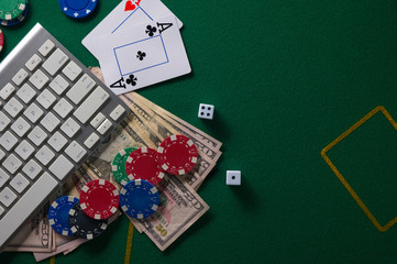Online poker. Chips and the dice nearby keyboard on green table top view copyspace