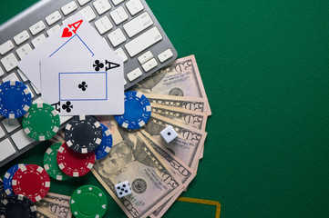 Online poker. Chips and the dice nearby keyboard on green table top view copyspace