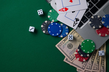 Gaming onlan business, online casino or casino. Green gaming table, laptop, money and chips. Game concept for design.