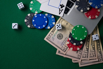 Online poker chips and dice near the keyboard on the gaming green table.