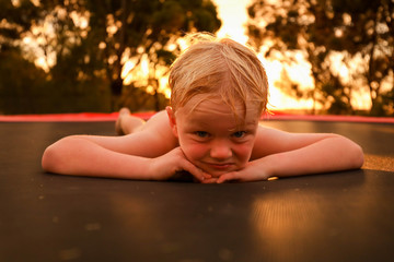 Little boy playing on trampoline at sunset