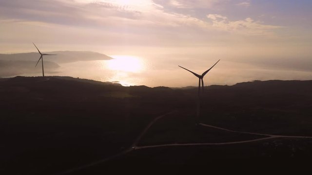 Wind turbines silhouette during sunset. Aerial dolly left