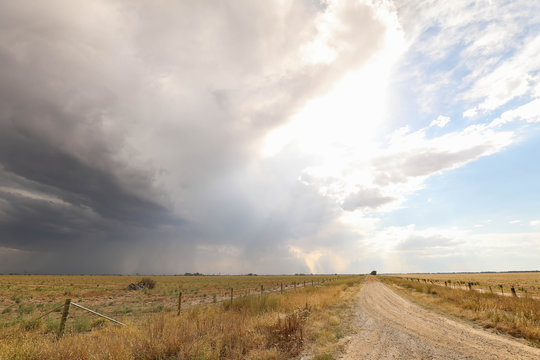 Storm on a country lane in remote central Victoria, Australia. Gravel road surrounded by dry paddocks in times of drought with the hopes of rain.