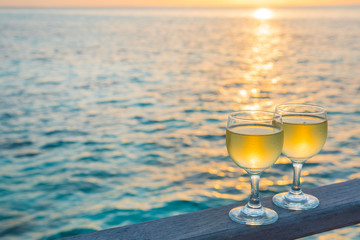 Romantic beach scene: two glasses of white wine at sunset near water line. Romantic luxury evening...
