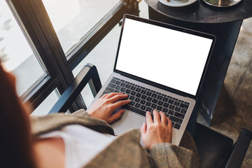 Top view mockup image of a woman using and typing on laptop computer with blank white desktop screen in cafe