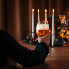 Young female holding glass of beer in romantic atmosphere with candle light.