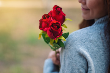 Closeup image of a beautiful asian woman holding red roses flower with feeling happy on Valentine's day