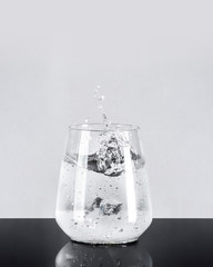 Water glass with ice and water splash