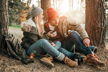 Travel couple camping with thermos in the forest. Concept of trekking, adventure and seasonal vacation.