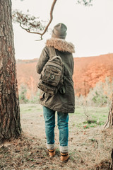 Hiking and travel along in the forest. Concept of trekking, adventure and seasonal vacation. Young woman walking in woods. Rear view of tourist on trail.