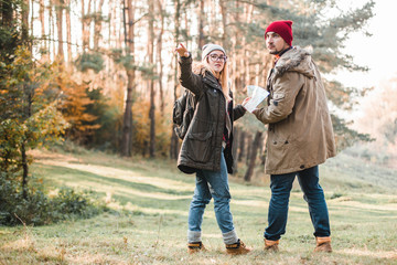 Travel couple with map, compass and backpack in the forest. Freedom and active travel concept.