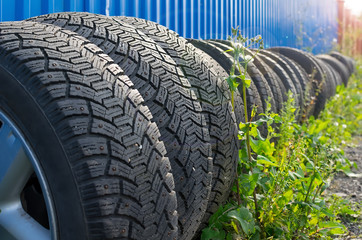 Obraz premium sets of car tires with disks are on the street on the ground near the fence of the cottage against the background of glare from the sun