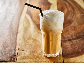 thai tea in glass with straw on wooden table top