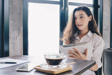 Portrait of happy young beautiful businesswoman working on tablet and waiting for her customer in cafe. Conceptual of businesswoman lifestyle.