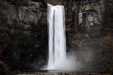 taughannock falls a silky smooth waterfall against a rock face cliff with splashing water at its...