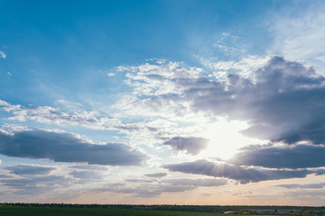 Evening sunset sky with bright rays of the sun and beautiful clouds