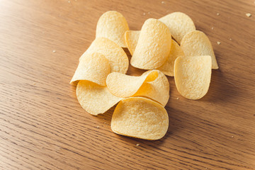 Delicious potato chips, laying on wooden table background