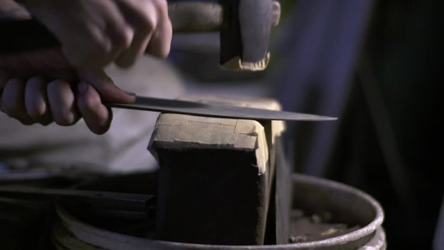 Japanese traditional knife smith in workshop. Craftsman delicately hammers a Japanese steel blade in slow motion. Captured on FS7 with Ziess CP50mm.