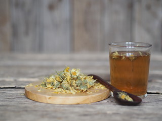 Dried flowers calendula and brewed medicinal tea on a wooden ancient table. Harvesting for the winter.