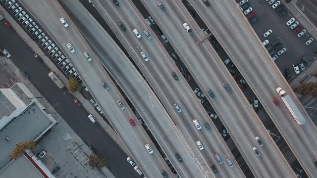 Aerial Drone Birdseye View Zooming Up out of Traffic Passing in Beautiful Busy Downtown Los Angeles overlooking Interstate 10 during Sunset 
