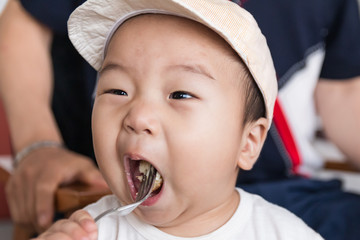 Little asian boy eating bread