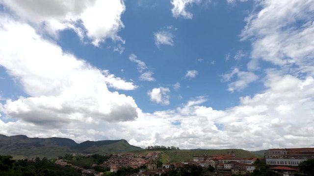 Daytime motion time-lapse of clouds against a blue sky passing by and leaving shadows on the colonial mining town of Ouro Preto in the valley below in Minas Gerais, Brazil