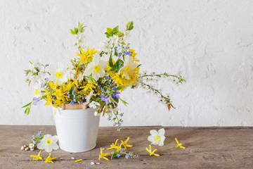spring flowers in white bucket on old wooden table