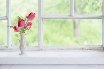 tulips in vase on white windowsill