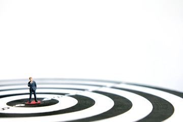 Business strategy conceptual photo - Miniature businessman thinking for goal plan at dartboard