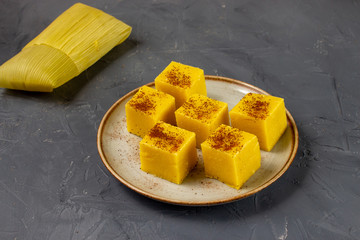 Pieces of Canjica or Curau. Tipical brazilian food made from corn. Festa Junina. In a plate on grey background.