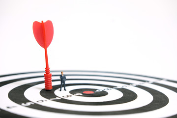 Business strategy conceptual photo - Miniature businessman with red arrow on a dartboard