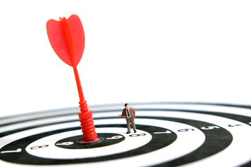 Business strategy conceptual photo - Miniature businessman pointing on red arrow on dartboard