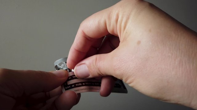 Close up female hands removing birth control pill from blister pack