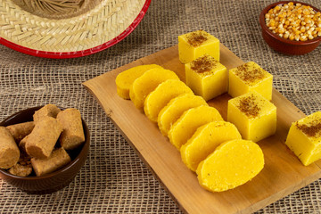 Pieces of Canjica or Curau. Tipical brazilian food made from corn. Festa Junina. In a piece of wood. with a tradicional hat.