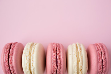 Row of white and pink macarons on pink