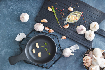 Fresh garlic with oil, spices and herbs on dark background