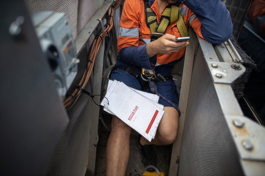 Building Maintenance Worker Is Using Cellphone Calling Site Emergency Services When Building Maintenance Unit Is Broken Down With Rescue Plan On His Leks At High Rise Building Sydney CBD Australia 