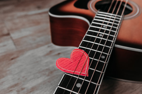 6 metal strings on a guitar and an eco-friendly paper heart on it, a picture for a loved one on a holiday or about a love of music