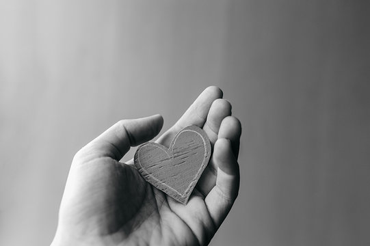 Black And White Image Small Paper Heart Hold Tight In The Palm Of Your Hand On A Background Of Gray Dirty Space