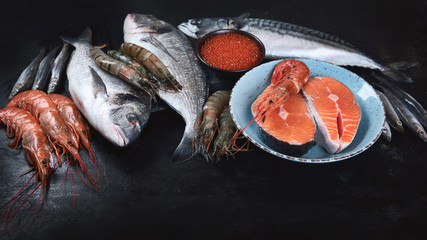 Fresh fish and seafood on black background.