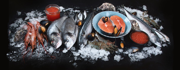 Fresh fish and seafood on black background.