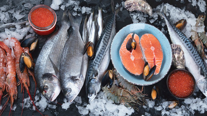 Fresh fish and seafood on black background.