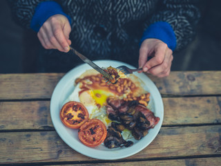 Young woman eating english breakfast in cafe